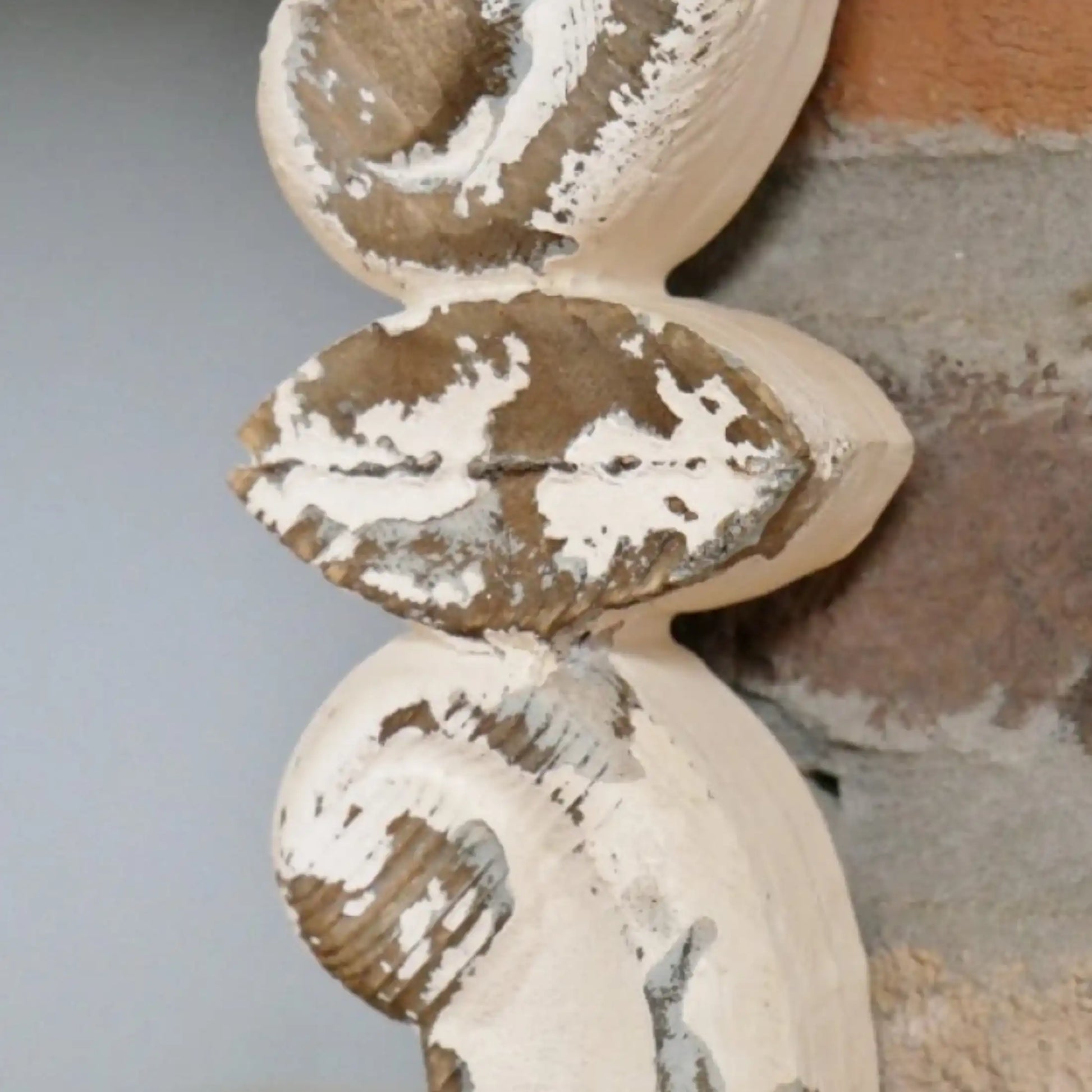 Decorative wooden finial with peeling paint on a neutral background