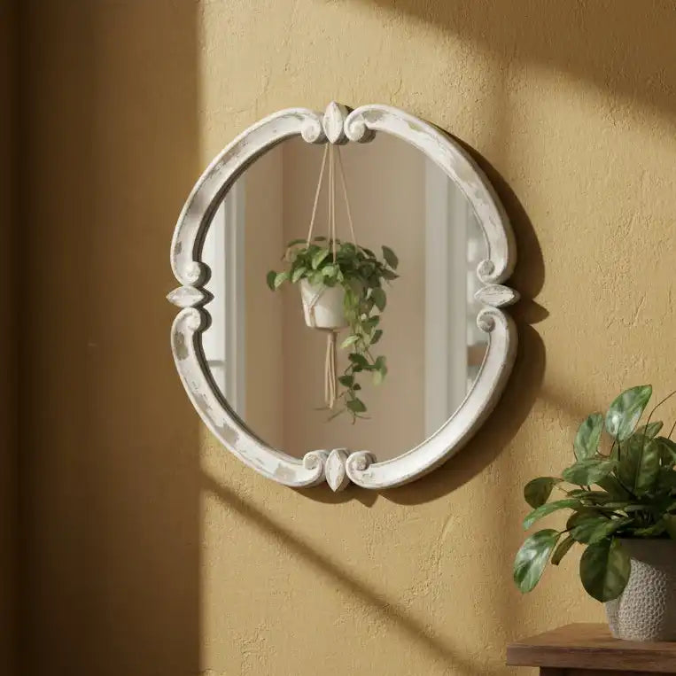 Decorative oval mirror with intricate details on a beige wall.