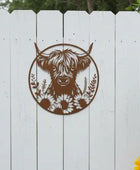 Decorative metal wall art of a bull with flowers on a white wooden fence.