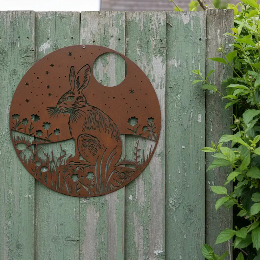 Metal decorative panel with a rabbit design on a wooden fence