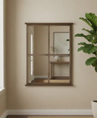 Wooden mirror with glass panels on a beige wall next to a potted plant.