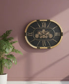 Decorative wall clock with mechanical design on a pink wall next to a potted plant.