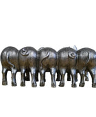 Set of six metallic buffalo figurines on a wooden surface with a stone wall background