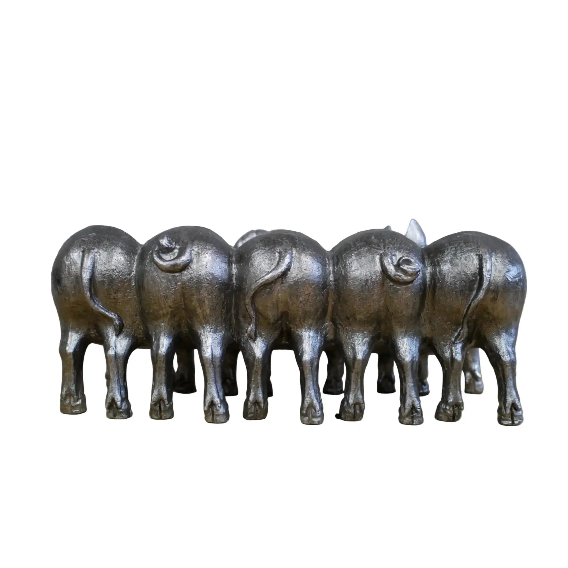 Set of six metallic buffalo figurines on a wooden surface with a stone wall background