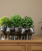 Five pig-shaped planters with green plants inside on a wooden surface.