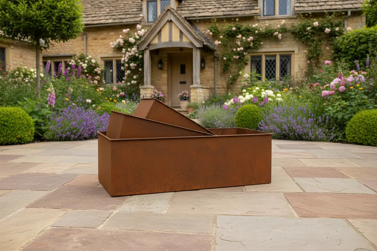 Rust-colored metal fire pit on a stone patio with a garden and house in the background