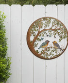 Decorative metal wall art with birds on a white picket fence