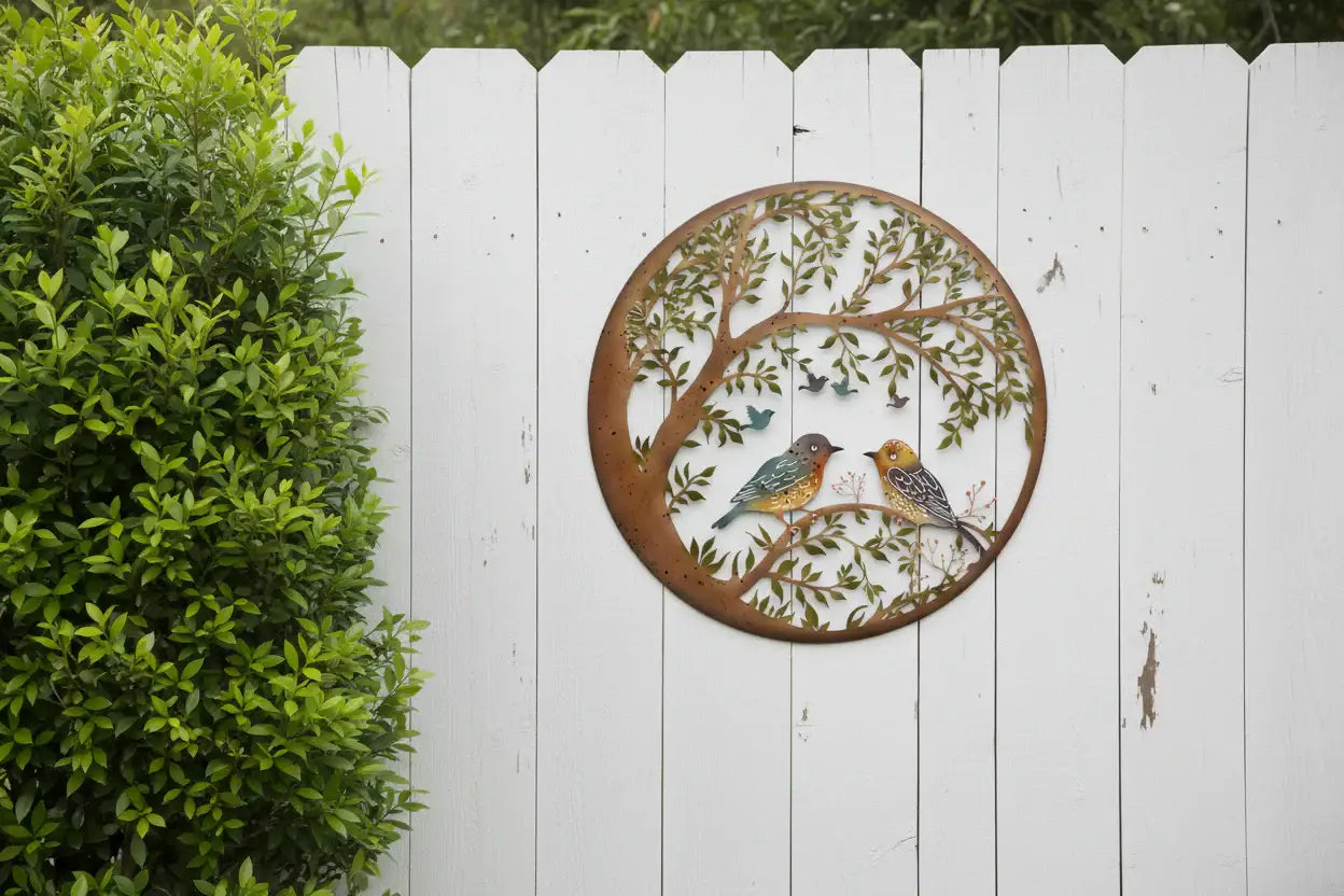 Decorative metal wall art with birds on a white picket fence