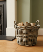 Wicker basket with firewood next to a fireplace in a room.