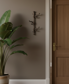 Hanging coat rack on a wall next to a wooden door with a plant in the foreground.