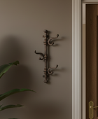 Decorative wall hook on a brown wall with a plant and wooden door in the background