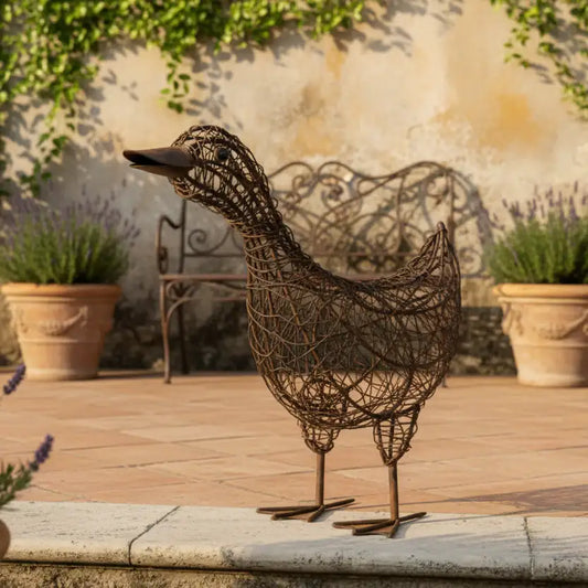 Decorative metal duck sculpture on a patio with potted plants and a stone wall in the background.