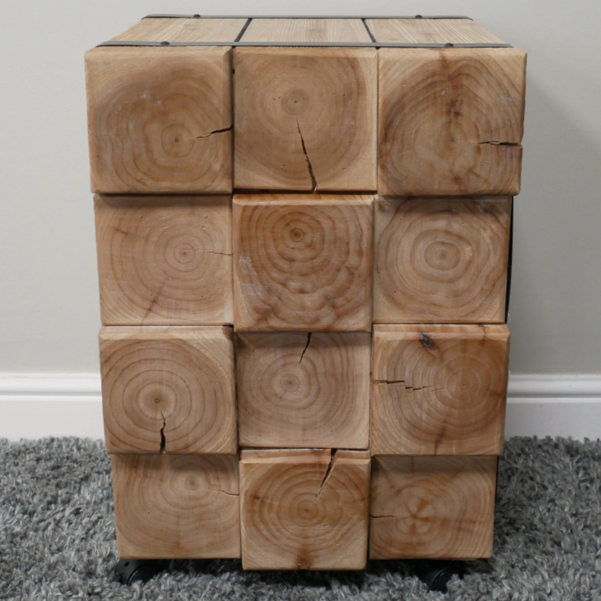 Wooden cube puzzle on a gray carpet with a white wall background