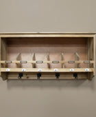 Wooden wall-mounted rack with numbered hooks on a beige wall.