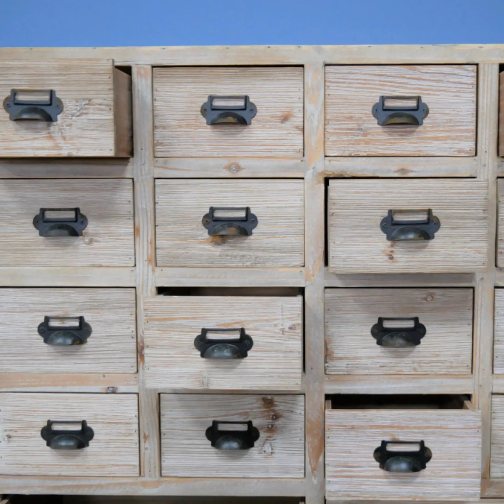 Wooden drawer unit with metal handles against a blue background