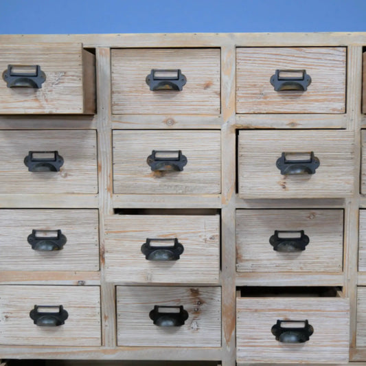 Wooden drawer unit with metal handles against a blue background