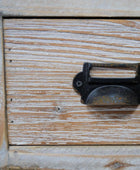 Wooden drawer with a metal handle showing signs of wear.
