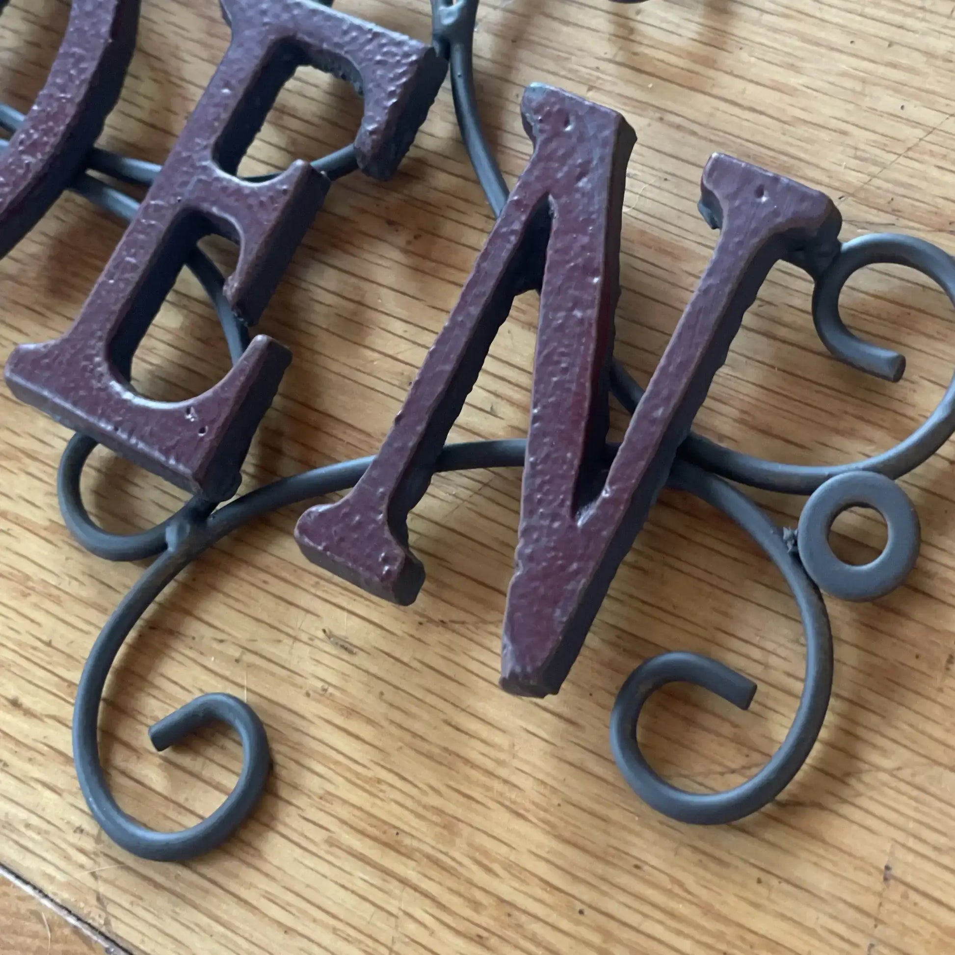 Decorative metal letters 'B' and 'V' on a wooden surface
