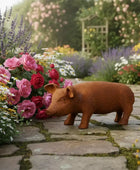 Decorative pig sculpture on a stone path with flowers and garden in the background