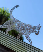 Decorative metal cat sculpture on a railing with a blue sky background