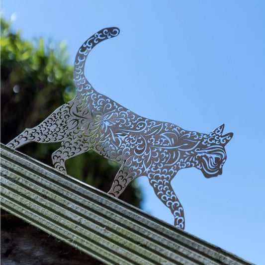 Decorative metal cat sculpture on a railing with a blue sky background