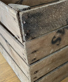 Close-up of a wooden crate with visible wear and a brand logo.