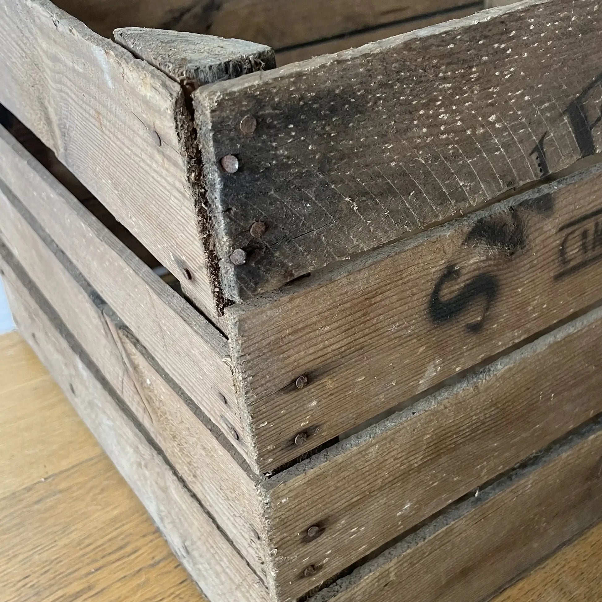 Close-up of a wooden crate with visible wear and a brand logo.