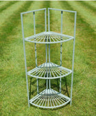 Three-tier metal corner shelf on a grassy background