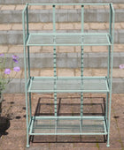 Green metal bakers rack with three shelves on a stone patio.