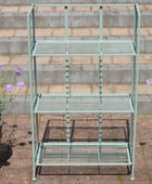 Green metal bakers rack with three shelves on a stone patio.