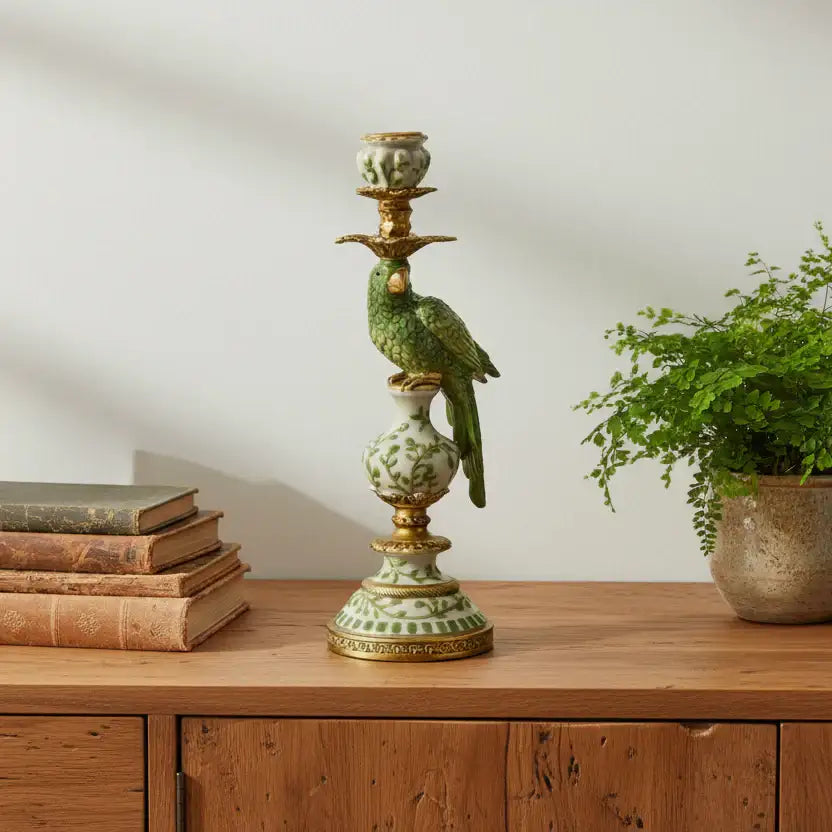 Decorative candlestick with a bird design on a wooden surface next to books and a plant.
