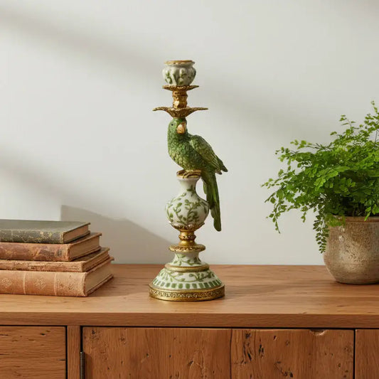 Decorative candlestick with a bird design on a wooden surface next to books and a plant.