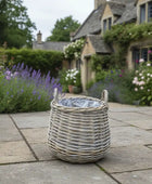 Wicker basket on a stone patio with a garden and house in the background