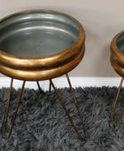 Two metallic side tables with bronze bases and gray tops on a dark gray rug.