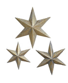 Three gold star-shaped wall decorations on a brick wall.