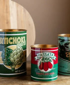 Three vintage-style canned food tins on a wooden surface with a dark background