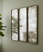 Three decorative mirrors with floral patterns on a wall.