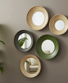 Set of round mirrors in various colors on a beige wall with a plant to the left.