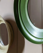 Two round mirrors, one green and one beige, on a wooden surface.