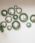 Wall with decorative mirrors in green frames and a plant on the left.