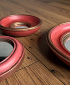 Three red ceramic bowls with gold rims on a gray fabric background