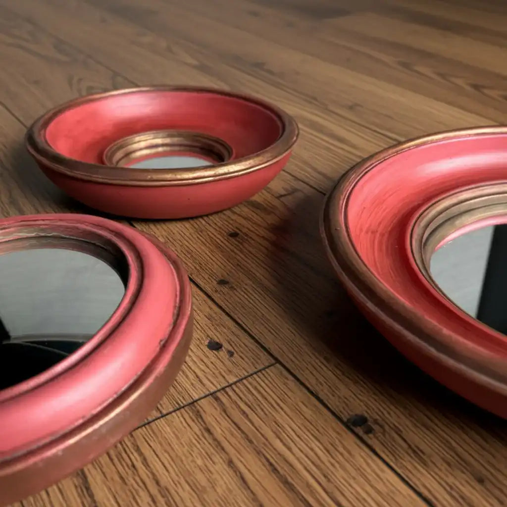 Three red ceramic bowls with gold rims on a gray fabric background