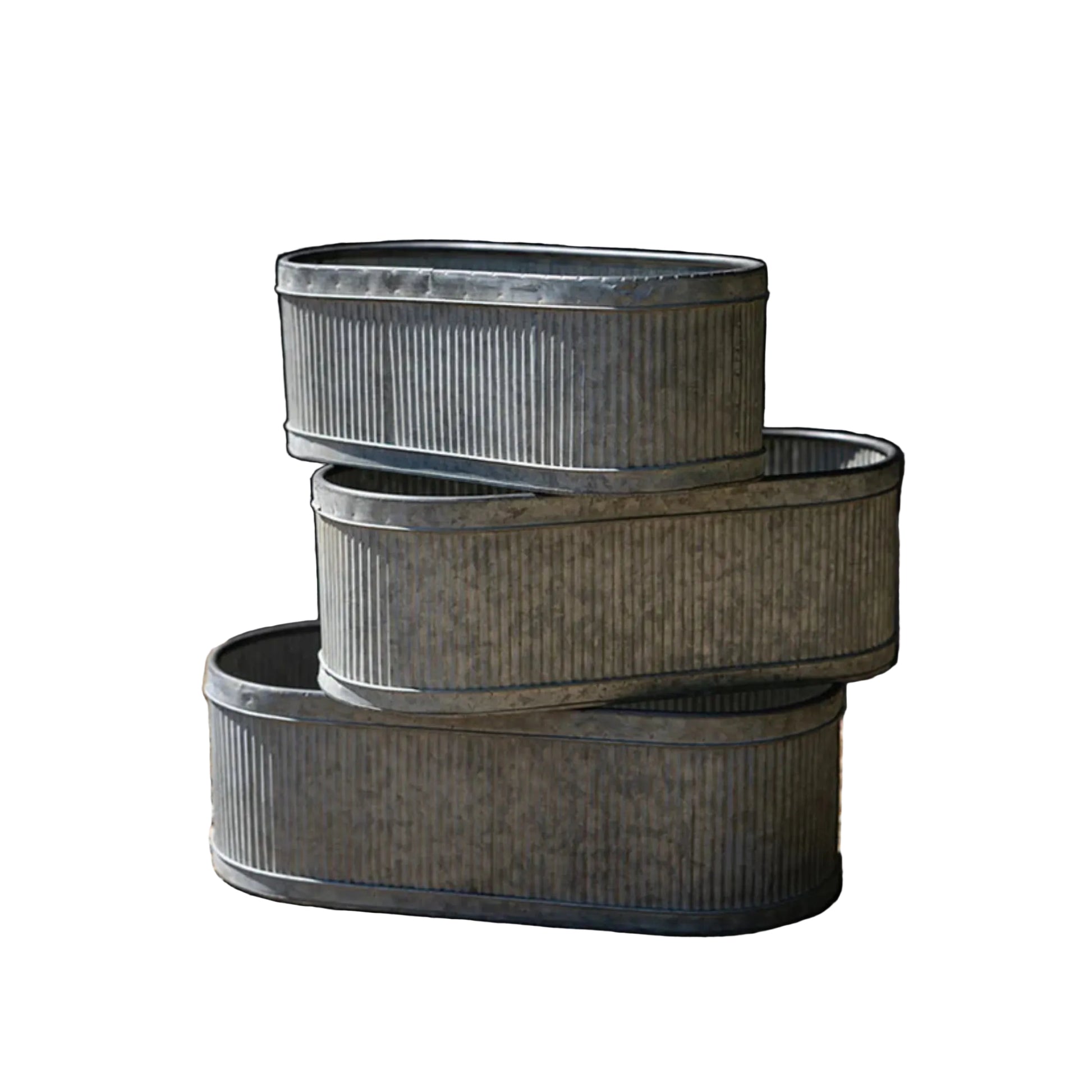 Three stacked metal planters on a gravel surface with a dark background