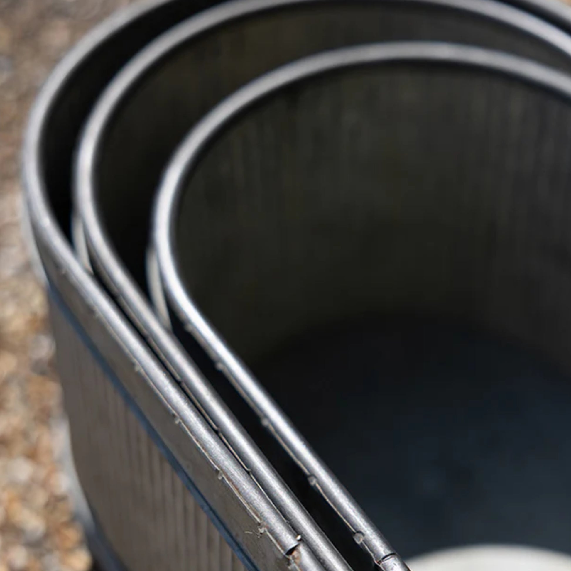Close-up of a set of metal buckets on a gravel surface
