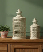 Two decorative lanterns on a wooden surface with a green wall background