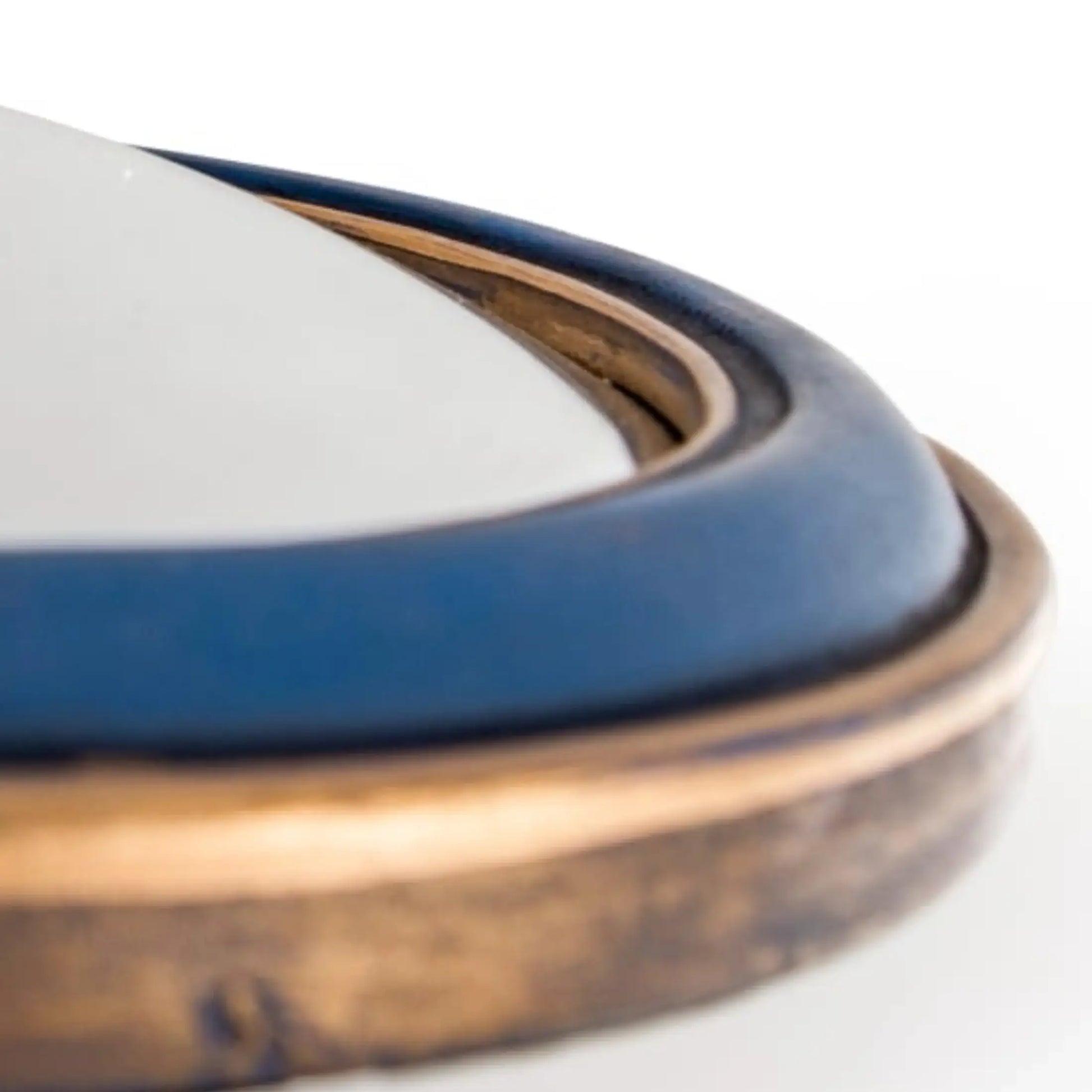 Close-up of a ceramic dish with blue interior and bronze exterior on a white background