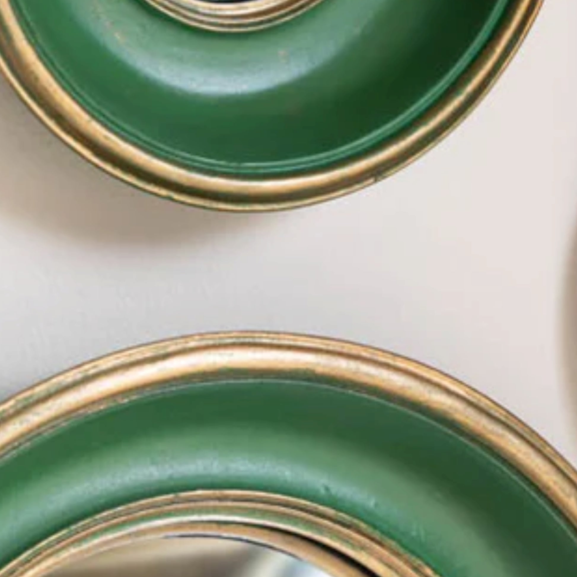 Two green plates with gold rims on a light background