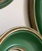 Close-up of green ceramic bowls with gold rims on a white background