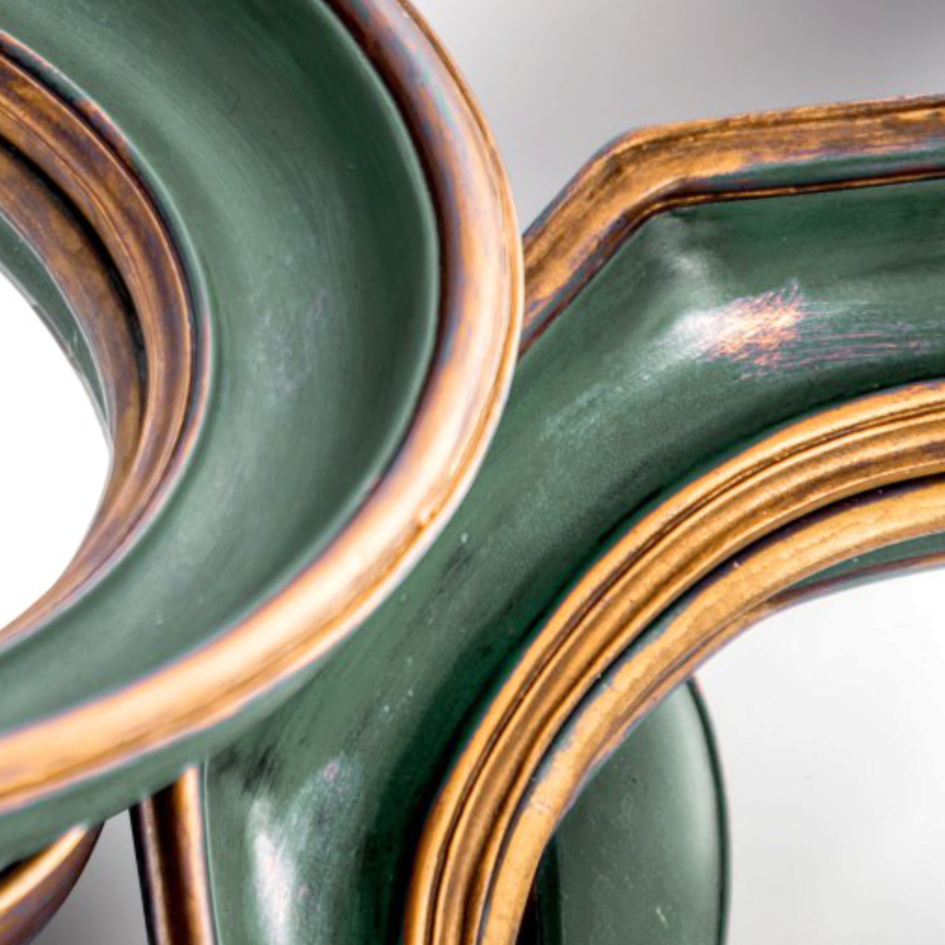 Close-up of green metal spools with gold accents on a reflective surface.