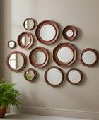 Wall with decorative mirrors arranged in a pattern, featuring a potted plant on the left.